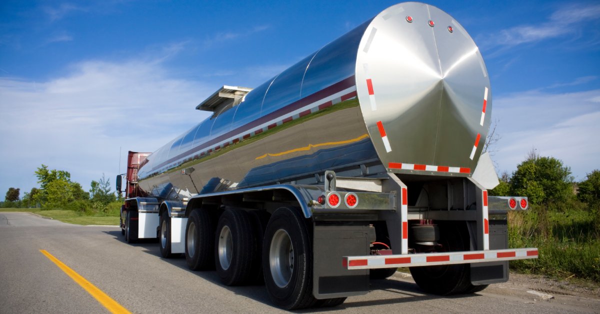 Closeup rearview of a chrome tanker trailer truck that transports gas or liquid cargo driving down the highway.
